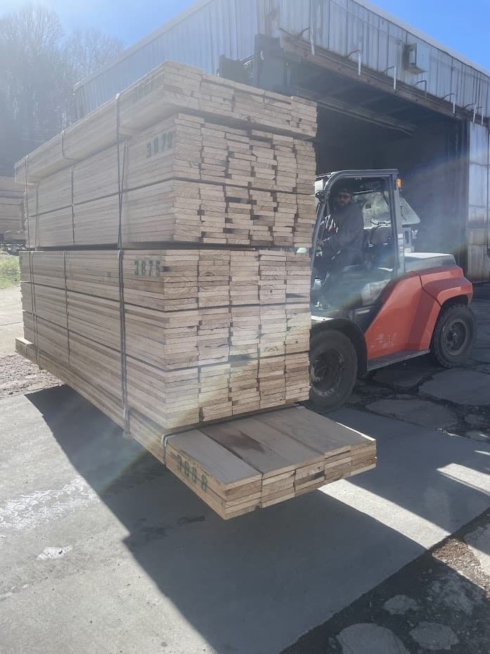 A forklift carrying a large pack of paulownia boards outside a mill